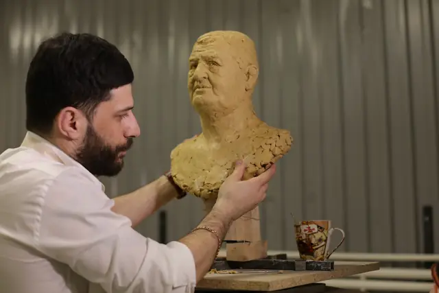 Скульптор смотрит на модель в профиль, проверяя линию шеи и затылка